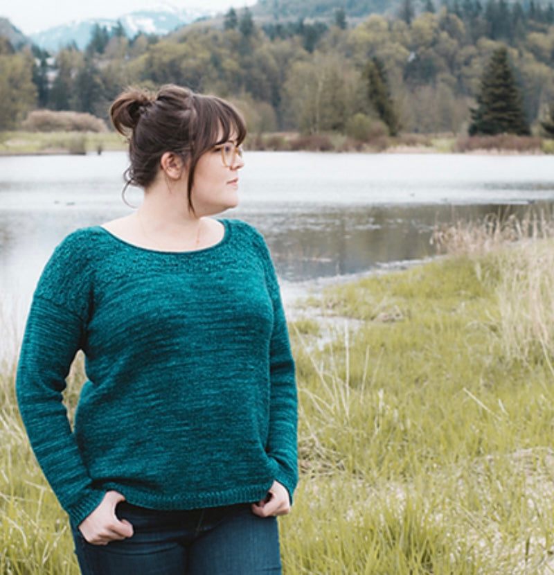 woman standing near water wearing hand knit sweater
