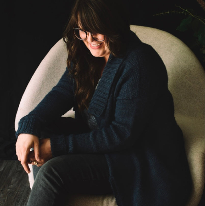 woman sitting in chair wearing hand knit cardigan