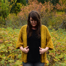 woman standing in forest wearing hand knit cardigan
