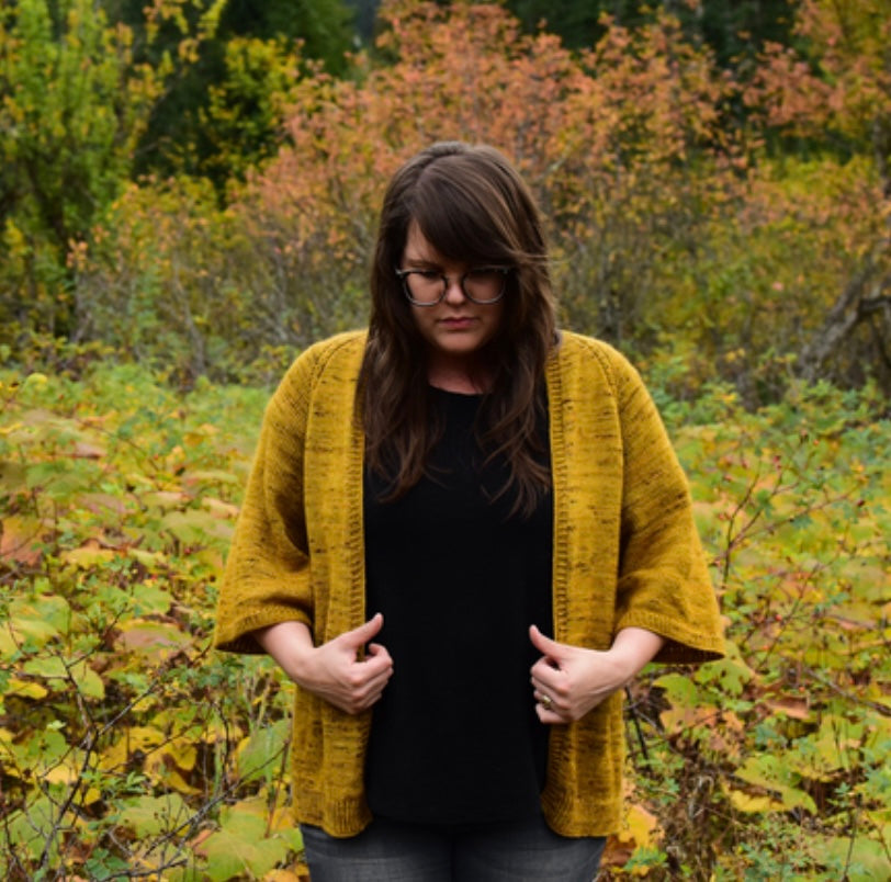 woman standing in forest wearing hand knit cardigan